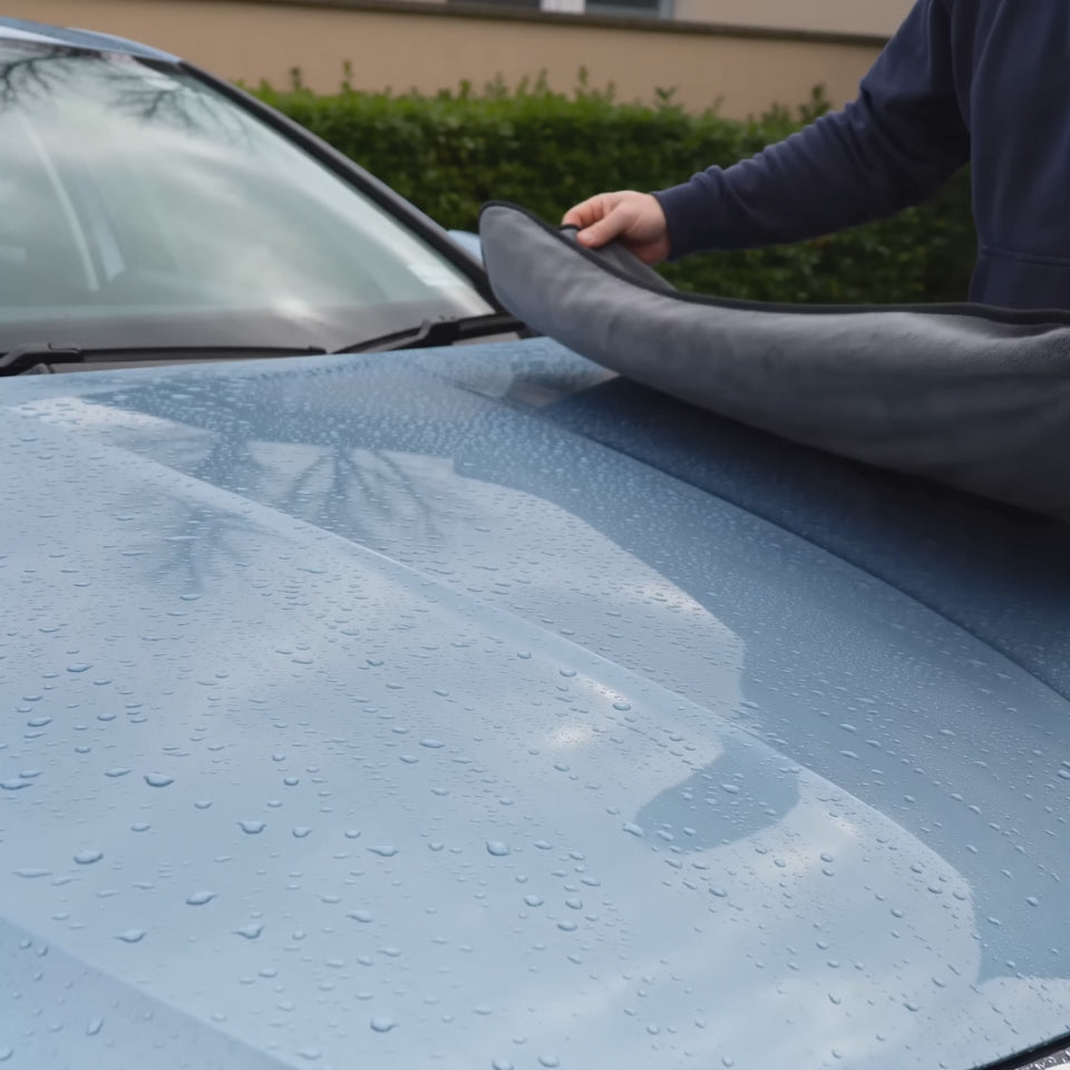 Mise en scène générée par IA : utilisation de la serviette microfibre Reflet Auto XL sur une voiture.